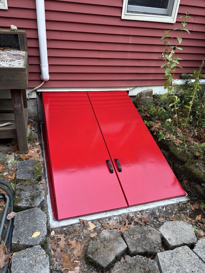New red steel bulkhead door sealed to the foundation of a house in Danville, NH
