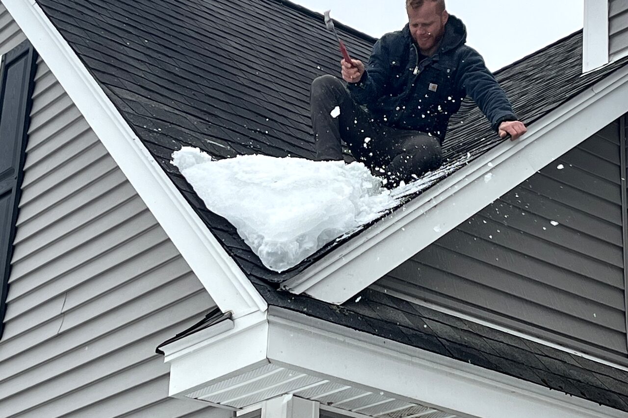 Clearing heavy snow from a steep residential roof in winter